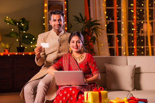 Indian asian young couple celebrating diwali and online shopping on laptop at home