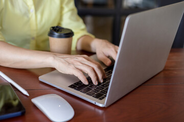 Business women in a yellow shirt working on laptop in office
