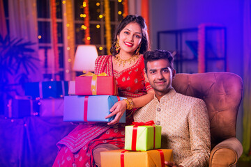 Indian young couple posing with gift boxes on diwali festival evening at home