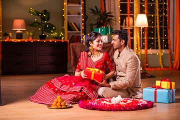 Indian young couple posing with gift boxes on diwali festival evening at home