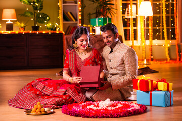 Indian young couple posing with gift boxes on diwali festival evening at home