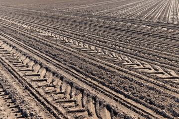 a plowed agricultural field with traces of a tractor