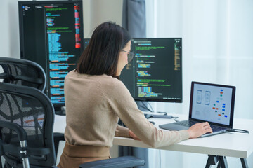 Asian prompt engineer develop coding app with software data sitting in front of computer monitor at...