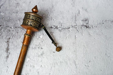 old prayer wheel or mani wheel with tibet mantra language made from copper and wood for Tibetan Buddhism on white concrete background