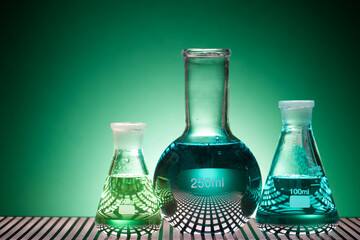 Glass flasks placed in a laboratory table with green liquid
