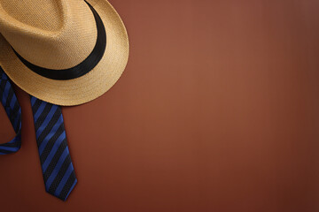 Father's day concept with fedora hat and necktie over brown background. top view, flat lay