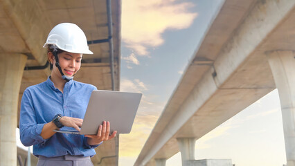Asian female engineer uses laptop to inspect highway construction work