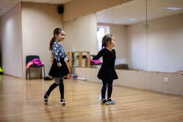 Two Young Girls Practicing Dance in Studio with Mirror Reflection