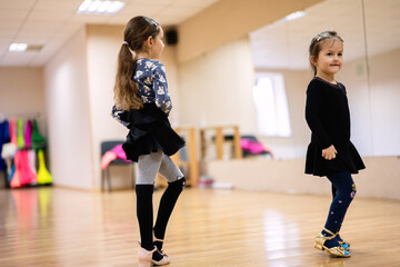 Two Little Girls Practicing Dance in Studio with Wooden Floor and Mirrors