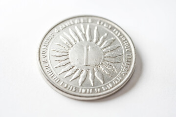 Close-up of a silver coin with a sun design