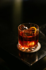 Cocktail with orange twist on dark background. Classic cocktail in bar.