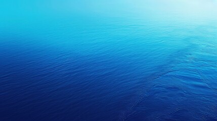 Obraz premium Deep blue ocean water surface with gentle ripples and a bright gradient across the top provides a calm background for environmental or travel advertising visuals.