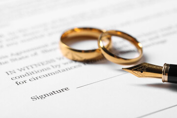 Fototapeta premium Marriage contract, gold rings and pen on table, closeup