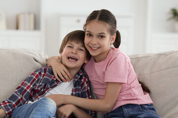 Obraz premium Happy brother and sister spending time together on sofa at home