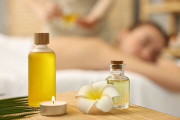 Aromatherapy. Woman receiving back massage in spa salon, focus on bottles of essential oils and...