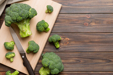 fresh green broccoli on wooden cutting board with knife. Broccoli cabbage leaves. light background....