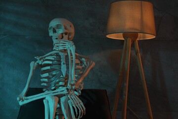 Waiting concept. Human skeleton sitting in armchair indoors
