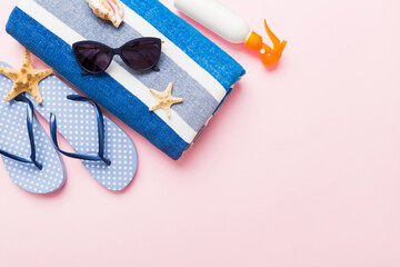 Summer holiday concept. Top view of beach towel, flip flop and sunscreen cream on table Top view...