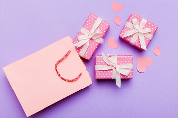 Gift boxes pop out from paper bag top view on colored background. bag packing handmade boxes fall out Concept of holidays, shopping, sale, discounts. Top view, flat lay