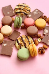 Pastel macarons, almond chocolate, peanut butter cookies and various nuts on bright pink background. Selective focus.