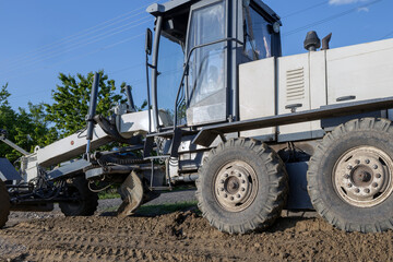 Obraz premium A grader levels gravel during road construction.