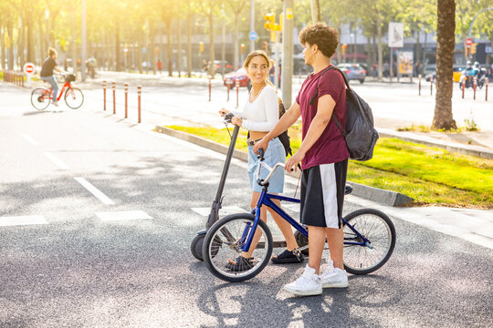 Happy latin couple in Barcelona going to seaside with bike and scooter