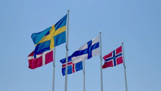 Scandinavian flags waving in the wind with blue sky background.