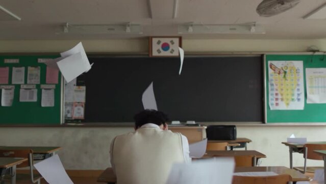 종이가 흩날리는 교실에서 좌절하는 학생