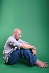 Adult Asian Bald Man Sitting Hugging His Knee On The Floor With Sad Expression 