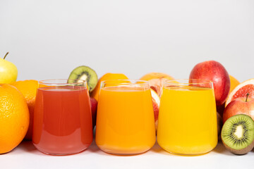 Different fruit juices in glasses on white background