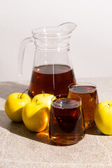 Apple juice in a glass and jug on a white background