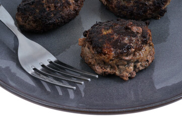 Boulettes de viande de bœuf maison servies dans une assiette avec une fourchette en gros plan sur fond blanc