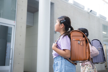 Elementary school students looking up with school bags on their backs Faceless back view