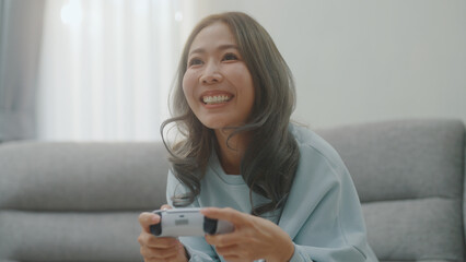 A woman is having fun playing a game with a controller on her favorite sofa.