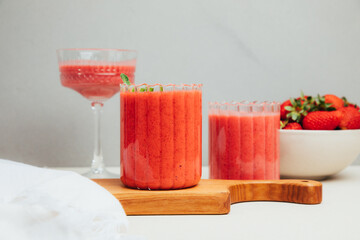Fruit smoothie in transparent cups. Red strawberry smoothie on a concrete background. The concept of healthy eating. Front view