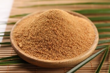 Coconut sugar, palm leaves and bamboo mat on table, closeup
