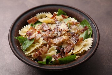 Tasty pasta with bacon and basil on brown table, closeup
