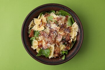 Tasty pasta with bacon and basil on light green table, top view