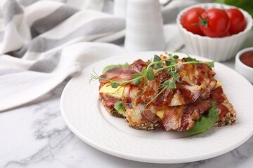 Tasty sandwich with bacon and microgreens on white marble table