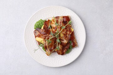 Tasty sandwich with bacon and microgreens on light grey table, top view