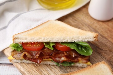 Delicious sandwich with fried bacon on wooden rustic table, closeup