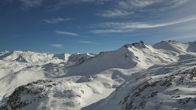 Drone shot of snowy mountains and ski slopes of Tignes in the French alps with a sunny cloudy sky