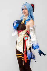 Female cosplayer with blue hair and an elaborate dress posing against a neutral background