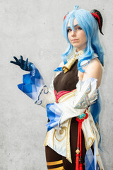 Female cosplayer with blue hair and an elaborate dress posing against a neutral background