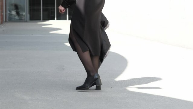 Detail of Asian girl with houndstooth coat in hand, showcasing fashion-forward street style in an urban setting.