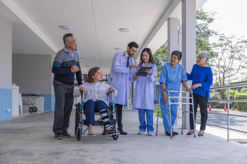 Doctors and nurse in hospital corridor with senior female and  senior male patient in walker and...