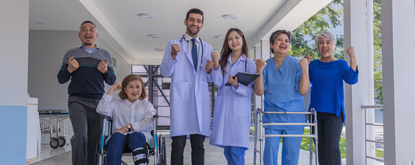 Doctors and nurse in hospital corridor with senior female and  senior male patient in walker and...