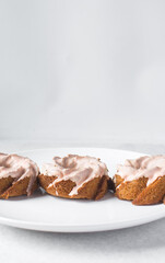 Iced mini bundt cake on a white plate, vanilla citrus bundlette on a plate, small vanilla bundt cake with an icing glaze