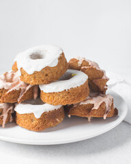 Iced mini bundt cakes stacked on a white plate, glazed vanilla and citrus bundlettes on a plate, small vanilla bundt cake with an icing glaze