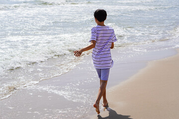 boy walking barefoot on the beach shore